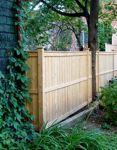 a wooden fence next to a tree and bushes