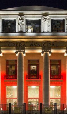 the opera municipal building lit up at night with red lights on it's windows