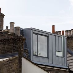 the roof of a building with chimneys and windows