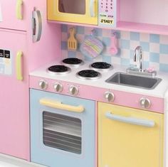 a toy kitchen with pink, yellow and blue appliances