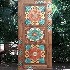 an artisticly painted wooden door in front of some trees