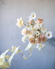 a bridal bouquet with white and pink flowers in it is being held by someone's hand