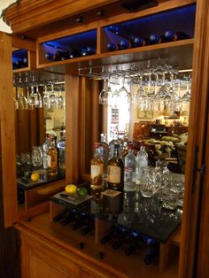 a wooden cabinet filled with lots of bottles and glasses