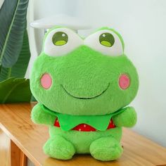 a green frog stuffed animal sitting on top of a wooden table