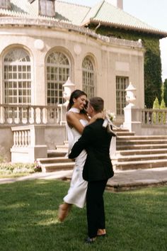 a bride and groom dancing in front of a mansion