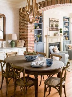 a dining room table with chairs and plates on it in front of a brick fireplace