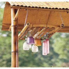 four lights hanging from the side of a wooden structure with bamboo poles and roofing