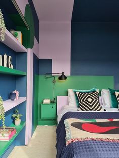 a bedroom with blue, green and white walls and shelves on the wall next to the bed