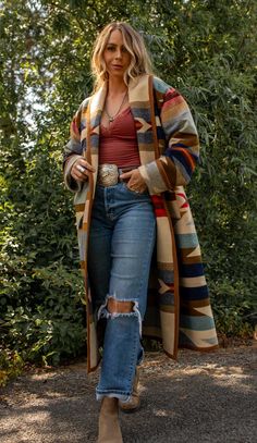 Wyeth Trail Long Stadium Coat Our Wyeth Trail Long Stadium Coat will keep you covered from top to below the knee. Made from the Pendleton Wyeth Trail wool blanket, the warm earth tone colors are easy to wear. Wear it open or close at the waist with a toggle. Designed for a slightly oversized fit and look. The Wyeth Trail blanket reflects warm, harmonious colors of ancient corn varieties patterned in rows similar to ancient Native American gardens. Arrows point in two directions, the past and the Pendleton Sweater Outfit, Warm Hippie Outfits, Western Thanksgiving Outfit, Warm Clothes Outfits, Blanket Coat Pattern, Yellowstone Outfit Ideas, Native American Poncho, Winter Country Outfits, Southwest Style Clothing