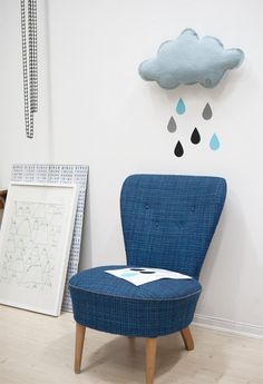 a blue chair sitting in front of a wall with a cloud on it's head