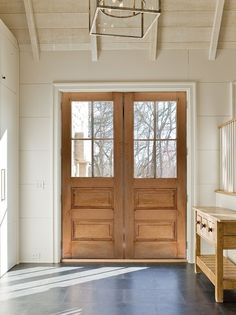 two wooden doors are open in a white room