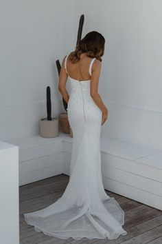 a woman in a white wedding dress looking down at the back of her bridal gown