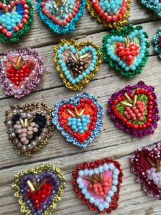 there are many small heart shaped beads on the wooden table with beaded hearts attached to them