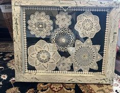 an old frame with crocheted doily on it sitting on top of a rug