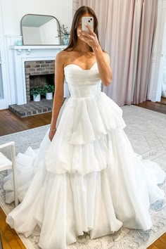 a woman taking a selfie wearing a wedding dress in front of a fire place