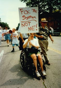 a man in a wheel chair holding a sign