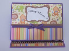 a colorful birthday card with monkeys and stripes on the front, purple ribbon around the edge