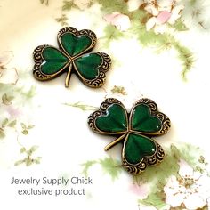 two green clover shaped brooches sitting on top of a table