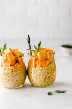 two small glass jars filled with food on top of a white counter next to each other