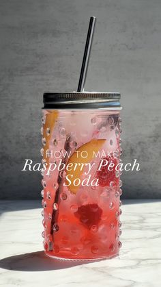 a mason jar filled with raspberry peach soda and topped with a black straw