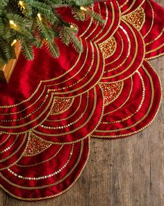 three red place mats with gold designs on them and a christmas tree in the background