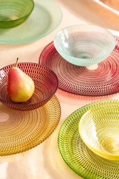 three plates with fruit on them are sitting on a tablecloth covered table, one has an apple in the center