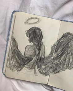 an open notebook with a drawing of two angel's wings on top of it