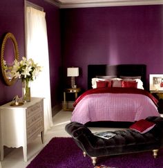 a bedroom decorated in purple and white with a bed, chair, dresser and mirror