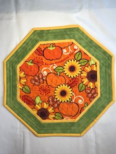 an orange and green plate with sunflowers, pumpkins and leaves on it