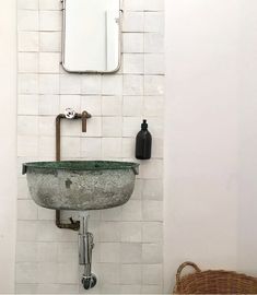 a bathroom sink sitting under a mirror next to a wall mounted soap dispenser