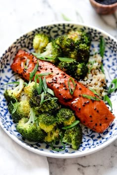 salmon and broccoli on a blue and white plate with sesame seed sprinkles