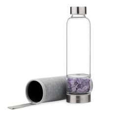 a glass bottle filled with purple rocks next to a roll of paper