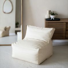 a white chair sitting in front of a mirror on top of a floor next to a dresser