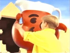 a man standing in front of a large orange and black teddy bear with a hat on it's head