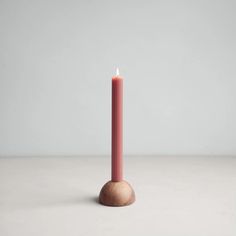 a pink candle sitting on top of a white table next to a wooden object with a light coming from it