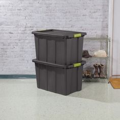 two plastic storage bins on the floor in front of a brick wall