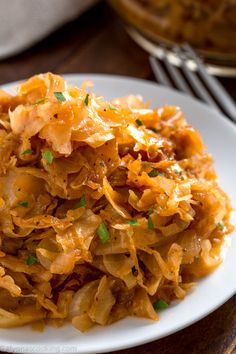 a white plate topped with cabbage covered in gravy and garnished with parsley