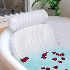 a bathtub filled with water and rose petals on the side, next to a window