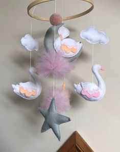 a crib mobile with swan, star and clouds hanging from it's sides