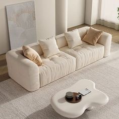 a living room with a white couch and coffee table on the floor in front of it