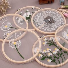 four embroidery hoop frames with daisies and dandelions in them on a table