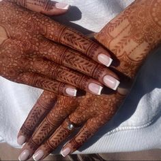 a woman's hands with henna tattoos on her hand and nails in the middle