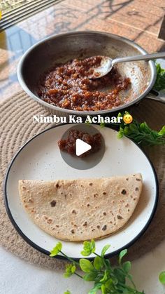 a plate with some food on it next to a pan filled with sauce and pita bread