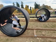 several people are playing in an outdoor play area with large tire shaped structures and wood slats