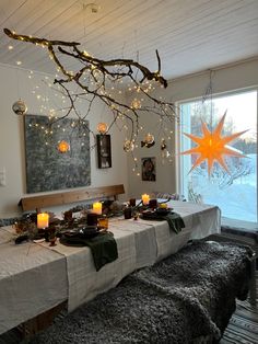 a long table with candles and decorations on it in front of a large star hanging from the ceiling