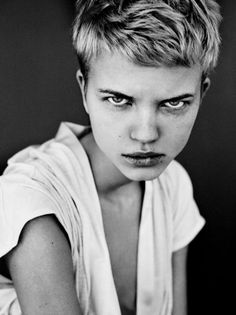 black and white photograph of a woman with short hair wearing a t - shirt looking at the camera