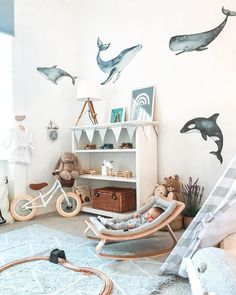 a child's room with dolphin decals on the wall and toys in rocking chairs