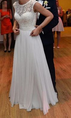 a woman in a white dress standing next to a man in a tuxedo