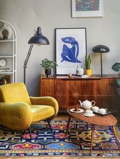 a living room with two chairs and a coffee table in front of a painting on the wall