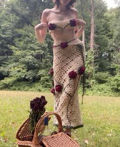 a woman in a crocheted skirt with roses on her chest and two wicker baskets next to it